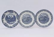 Lote 22 - Três pratos em porcelana estampilhada de azul com rebordo ornamentado de elementos vegetalistas e cena central figurativa, marcados na base, um made in England by Johnson Bros, Stoke-on-Trent, Coaching Scenes, outros dois marcados Royal Wessex, made in England, com 25 cm de diâmetro. Pequenos sinais de uso