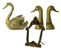 Lote 2628 - Conjunto em metal dourado composto por 1 floreira em forma de cisne cinzelado Dim: 27x23x13 cm. 1 espelho de mesa com moldura em bronze trabalhado, marcado na aste de apoio, Dim: 32x24 cm. Par de cerra livros em forma de cabeça de pato Dim: 23