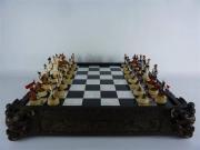 Lote 26 - Tabuleiro de xadrez com 2 gavetas ricamente trabalhado, com peças em resina moldada, representativas da guerra entre França e Áustria, com 11x52x52 cm