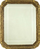 Lote 4236 - Espelho com decoração biselada inserido em moldura dourada de madeira entalhada, ricamente decorada com frisos de enrolamentos vegetalistas e concheados em gesso, com a dimensão aproximada de 82x66 cm. Nota: Em bom estado