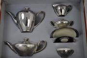 Lote 1137 - Estojo com serviço de chá em porcelana prateada e salva oval de casquinha (33x46 cm), composto por 2 bules, açucareiro, leiteira, chávena, pires e prato de doce