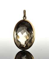 Lote 6003 - PENDENTE DE QUARTZO FUMADO EM OURO 19.2 KT - Aro e argola de suspensão em Ouro com Quartzo Fumado de 50.00 ct. de elevada pureza em talhe oval facetado. Peso: 11.86 g. Dim: 36x23 mm. Valor estimado de € 1.200 em ourivesaria. Nota: Como novo, c