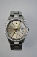 Lote 524 - Relógio *ORIGINAL* da marca ROLEX, modelo Oyster Perpetual Date, de aço, movimento automático, mostrador metalizado com indicação de data, horas assinaladas por travessões, bracelete de aço com fecho de báscula, caixa de aço com aro cravejado c