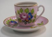Lote 38 - PORCELANA - Chavena com pires em porcelana da EMA pintado á mão em tons rosa com motivos florrais. Pires com 11 cm de diâmetro