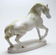 Lote 381 - CAVALO - Estatueta de Cavalo em porcelana portuguesa de cor branca com apontamentos a bege, sobre base oval, marcada na base. Dimensão: 26x11,5x26 cm. Falha numa orelha