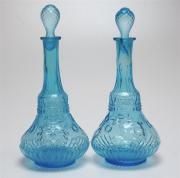 Lote 396 - GARRAFAS - Par de garrafas em vidro tom de azul biselado com tampa. Dim: 38cm altura. Nota: sinais de uso