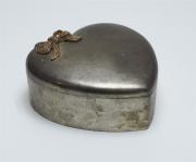 Lote 394 - CAIXA METAL CORAÇÃO - caixa em metal em formato de coração, com decoração relevada em forma de laço dourado. Forrada a veludo branco. Dimensões: 5 x 13 x 13 cm