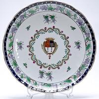 Lote 163 - PRATO ORIENTAL - Prato em porcelana oriental chinesa policromada ornamentado com brasão de armas envolto em coroa de flores e com rebordo com cacho de uvas e parras, marcado na base, com 30,5ø cm. Bom estado geral, ligeiro desgaste