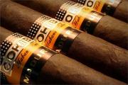 Lote 6077 - COHIBA, CHARUTOS - Caixa em madeira com 25 Charutos Genios Maduro 5. Caixa similar à venda por € 834. Nota: conserva a caixa exterior em cartão com o selo de garantia da República de Cuba e da República Portuguesa. Consultar valor indicativo em https://www.cgarsltd.co.uk/cohiba-maduro-magicos-cigar-box-p-4226.html