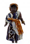 Lote 24 - BONECA DE PORCELANA - Nigéria. Boneca em porcelana vestida com roupas representativas dos trajes regionais do seu pais, com aproximadamente 21,5 cm de comprimento. Nota: sinais de armazenamento