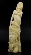 Lote 6047 - ARTE TRIBAL AFRICANA, ESCULTURA EM MARFIM - Representando busto feminino com decoração entalhada, encimado por figura feminina sentada. Dim: 37 cm. Peso: 2.180 g. Proveniente de Moçambique, década de 60 do século XX