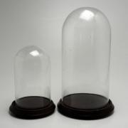 Lote 212 - REDOMAS - duas redomas redondas em vidro com bases em madeira. Dimensão: 28 cm e 43 cm de altura. Sinais de uso