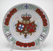 Lote 20 - COLEÇÕES PHILAE - Prato decorativo em porcelana em homenagem ao Casamento de Sua Alteza Real D. Duarte Pio, Duque de Bragança com a Excelentíssima Senhora Dona Isabel de Herédia 13 de Maio de 1995 Igreja de Stª Maria de Belém. Edição limitada e exclusiva Coleções Philae. Decoração policromada monárquica com elementos a ouro. Diâmetro : 24cm.