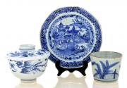 Lote 7 - CONJUNTO EM PORCELANA ORIENTAL - Composto por prato, copo e taça com tampa. Decorações a azul e branco com cenas de paisagem e motivos vegetalistas. Dim: 15 cm (diâmetro do prato). Nota: sinais de uso e desgastes