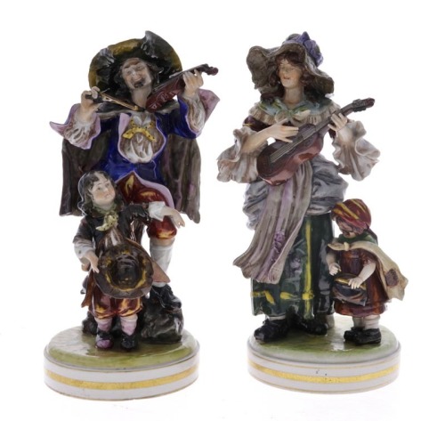 Lote 5107 - ESTATUETAS EM PORCELANA AO ESTILO CAPO-DI-MONTE - Conjunto de 2 estatuetas representando musicos com meninos em porcelana relevada e policromada, assente sobre base circular. Marcadas com N coroado. Dim: 33 cm (altura). Nota: sinais de uso, 1 