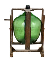 Lote 5331 - GARRAFÃO DE GRANDES DIMENSÕES EM VIDRO COM SUPORTE - Garrafão em vidro verde com suporte em madeira. Dim: 62x46 cm (garrafão) e 77x64x52 cm (suporte). Nota: sinais de uso e vestígios de xilófagos