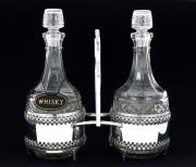 Lote 105 - GARRAFAS EM VIDRO - Conjunto de duas garrafas em vidro com suporte em metal cromado. Com chapa "Wisky". Dim: 28 cm (altura garrafa). Nota: desgastes no cromado