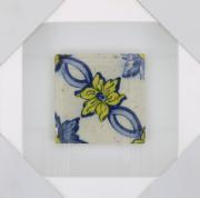 Lote 47 - AZULEJO, SÉC. XVIII - Azulejo antigo aplicado em moldura vitrine (branca). Decoração em tons de azul e amarelo, pintado à mão, com motivos florais. Dim: 14x14 cm (azulejo), 29,5x29,5 cm (moldura). Nota: sinais de manuseamento