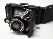Lote 4193 - CÂMARA ZEISS ICON - máquina fotográfica dobrável de fole da marca Zeiss Icon, modelo Nettar 512/2, ano de lançamento em 1937, filme 120 (exposições de 6 × 9cm), visor óptico de visão indireta na lente, Nettar Anastigmat 1: 4,5 / 11cm no obturador de folhas de Telma. Dimensão: 9x16,5x4,5 cm (fechada), com bolsa em couro castanho. Sinais de uso. Nota: http://camera-wiki.org/wiki/Nettar#Nettar_515.2F2
