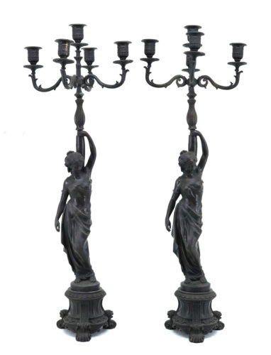 Lote 5099 - PAR DE CANDELABROS DE 5 LUMES EM BRONZE SÉC. XIX/XX- Decoração profusa com figura de mulher Romana assente em base redonda com tripé em formato de voluta e com saial inferior recortado. Dim. 76x26cm. Nota: bem conservado