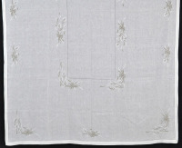 Lote 2 - TOALHA DE LINHO COM BORDADOS - Toalha de mesa em tecido de linho branco, bordada à mão em linha branca e bege com desenho de flores e laços, remate em ponto ajour. Dim: 170x260 cm. Nota: sem uso