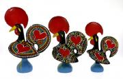 Lote 12 - GALO DE BARCELOS - Conjunto de 3 Galos de Barcelos em barro, de diversas dimensões, pintados à mão em policromia com motivos florais e corações. Dim. 25 cm de altura (maior). Nota: sinais de armazenamento