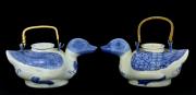 Lote 180 - BULES EM PORCELANA CHINESA - Par de bules em forma de patos, em porcelana marcada na base, decoração em azul pintada à mão, com pegas em bambu. Dim: 21 cm de comprimento. Nota: sinais de manuseamento