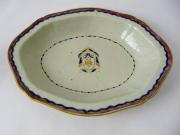 Lote 1920 - Covilhete em porcelana antiga Companhia das Índias, em vidrado branco e decoração com filet azul e rosa, c/ brasão no centro. Pequena interrupção no filet azul. Dimensões: 29x23cm.