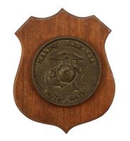 Lote 89 - ESCUDO NAVAL EM MADEIRA E BRONZE - Escudo em madeira de formato recortado com aplicação de placa em bronze relevado com as inscrições "Marine Barracks" e "Rota Spain". Dim: 33x26 cm