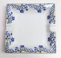 Lote 110 - CINZEIRO DE PORCELANA SPAL - Cinzeiro em porcelana, decorado com motivos florais em tons de azul e rebordo amarelo, da marca SPAL, forma nº2, com decoração "Marquise", desenhada por Sylvie Prenant e datada em 1994. Dimensões: 17,2x17,2x3,8cm