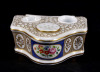 Lote 42 - TINTEIRO EM PORCELANA EUROPEIA - Formato recortado com 3 reservatórios em porcelana, decoração floral policromada com ornamentos dourados. Dim: 4x10x11 cm