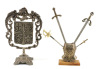 Lote 158 - PANÓPLIA E ESTANDARTE - Conjunto de 2 peças em metal com decoração em relevo, composto por panóplia assente em base de madeira e estandarte com brasões com suporte decorado com elementos vegetalistas. Dim: 33 cm (estandarte)