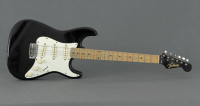 Lote 23 - "JIM HARLEY", GUITARRA ELÉCTRICA - Estilo Stratocaster. Preta e branca. Dim: 98 cm. Nota: 2 cordas partidas e sinais de uso. Apresenta saco de transporte