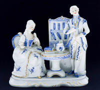 Lote 224 - CENA GALANTE - Grupo escultórico em porcelana, representando Cena Galante, decoração em azul com frisos dourados. Dim: 20x22x12 cm