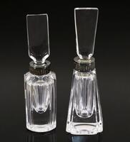 Lote 276 - ATLANTIS, FRASCOS DE PERFUME - Conjunto de 2 frascos de perfume em cristal com aplicações em metal nos gargalos e rolhas com vareta. Dim: 13 e 13,5 cm respectivamente