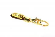 Lote 37 - Porta chaves em metal dourado, fita em pele castanha entrançada com decoração de círculos vazados em metal dourado, com 11 cm de comprimento, em embalagem, Nota: como novo
