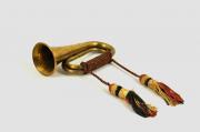 Lote 2085 - Instrumento de sopro antigo, possivelmente inglês, em metal amarelo, com cordões e borlas de seda, com brasão e insígnia imperial, com legenda latina. Sinais de uso. Dimensões: 28x12,5cm.