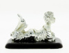 Lote 114 - ESTATUETA EM PRATA LAMINADA - Com decoração relevada representando figura feminina deitada, assente em base de madeira. Com pvp de € 48,24. Dim: 8,5x7x13 cm - 2