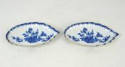 Lote 137 - Par de covilhetes em forma de folha recortada em porcelana VA, Mottahedeh, decoração floral a azul com friso dourado, com 3x25,5x15 cm