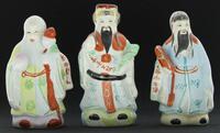 Lote 224 - IMORTAIS, ESTATUETAS DA MITOLOGIA CHINESA - Conjunto de 3 figuras em porcelana representando os 3 principais Imortais Orientais com as suas vestes coloridas em tons secos e claros. Dim: aproximada 15 cm de altura, cada