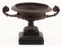 Lote 45 - TAÇA COM PEDESTAL - Taça em resina patinada de escuro com decoração gravada e 2 asas assente em base quadrangular. Dim: 17 cm (altura)