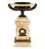 Lote 63 - TAÇA COM PEDESTAL - Taça em resina patinada de negro e marfim simulando com decoração gravada e 2 asas assente em base de resina patinada de negro e marfim com coroas de louros. Dim: 33 cm