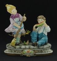 Lote 328 - CAPODIMONTE, ESCULTURA EM PORCELANA E BISCUIT - Representando figuras de crianças sobre base naturalista com decoração policromada e dourada. Dim: 16x15x7 cm. Nota: marcada na base