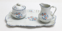 Lote 131 - PORCELANA LIMOGES - conjunto em porcelana francesa Royal Limoges composto por bandeja, leiteira e açucareiro estampados com motivos florais policromados, perlados em relevo e filete azul no bordo, marcado na base. Dimensão: bandeja 30,5x21,5 cm