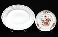 Lote 179 - VISTA ALEGRE, PRATO E TRAVESSA EM PORCELANA - Conjunto de 2 peças marcadas na base (1971-1980), sendo: travessa de formato oval com decoração a branco e aba gomada; e prato com decoração bordeaux com motivos florais. Dim: 4x34x27 cm