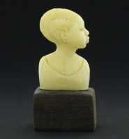 Lote 192 - ARTE AFRICANA - Busto feminino em osso entalhado, assente em base de formato rectangular de madeira exótica. Dim: 11,5 cm de altura