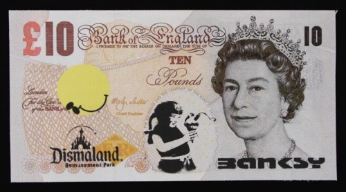 Lote 10 - BANKSY (AFTER) - Impressão sobre tela com assinatura, Edição Dismaland August/September 2015, título "Dismal 10 Pound". Verso com inscrição. Dim: mancha 11x21 cm. Sem moldura. Nota: Banksy (n.1974) é um artista britânico de rua, cujos trabalhos 