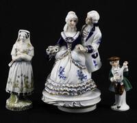 Lote 112 - FIGURAS EM PORCELANA - Conjunto de 3 peças em porcelana com decoração policromada, modelos e decorações diferentes. Sinaias de uso, pequenas falhas. Dim: 18 cm (maior)