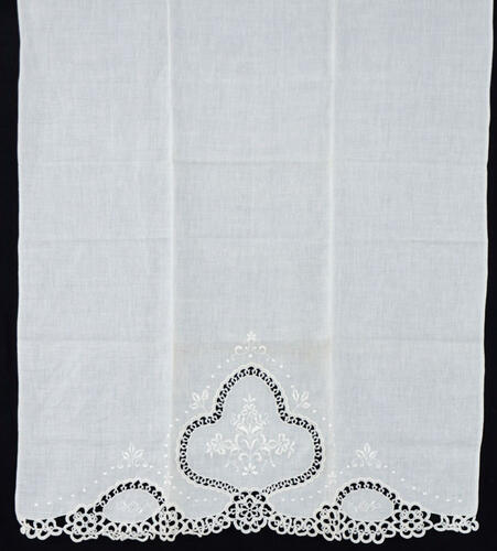 Lote 26 - TOALHA EM LINHO COM BORDADOS E RENDA DE CROCHET - Toalha em tecido branco de linho com barra bordada à mão com desenho floral e remate em renda de crochet. Dim: 70x104 cm. Nota: sem uso