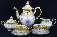 Lote 76 - BAVARIA, TÊTE À TÊTE EM PORCELANA - Conjunto de 7 peças em porcelana marcada na base, decoração floral policromada com ornamentos em dourado, composto por bule, leiteira, açucareiro e par de chávenas de café com pires. Dim: 18 cm (bule)